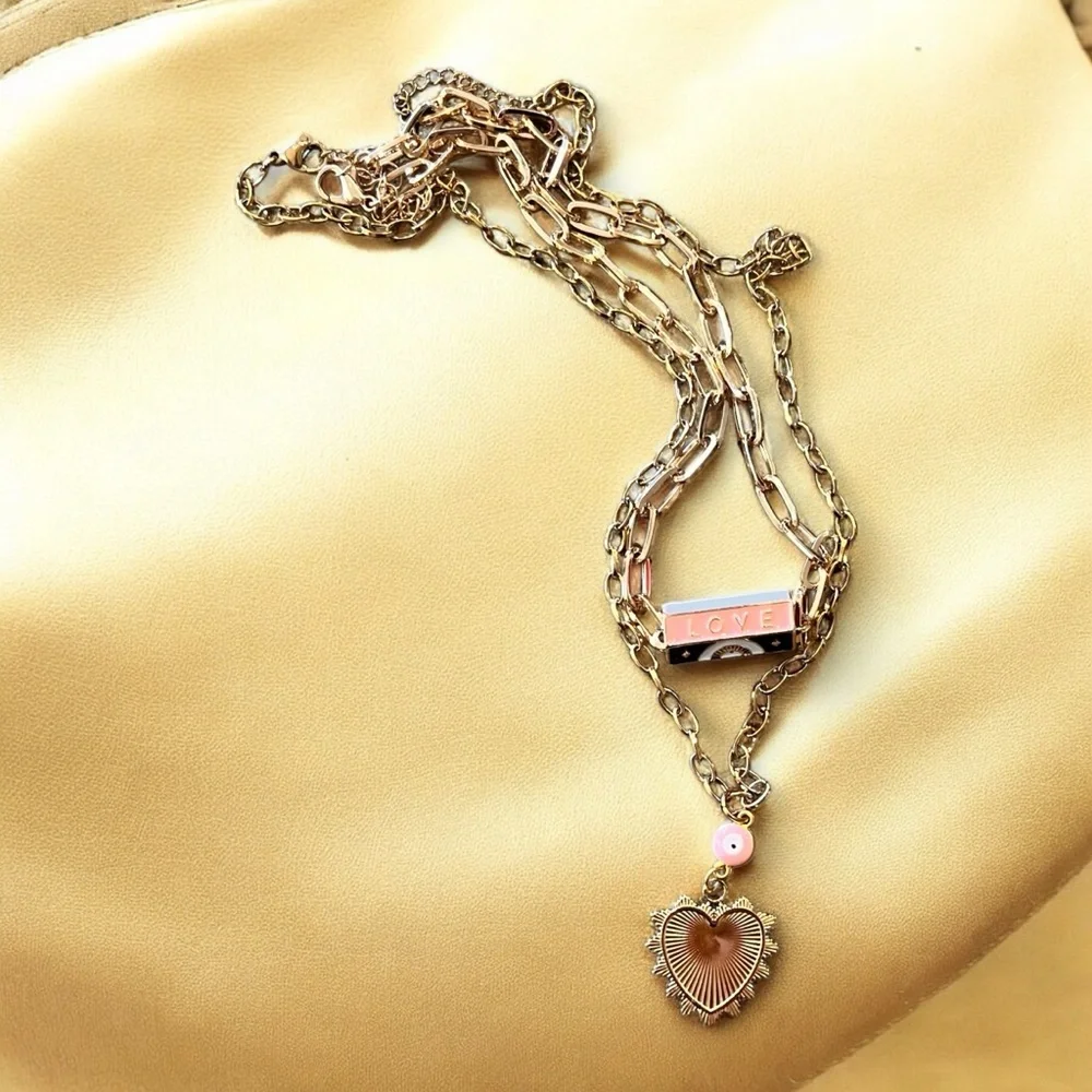Gold toned chains with black, white, gold, and pastel pink enamel charms.